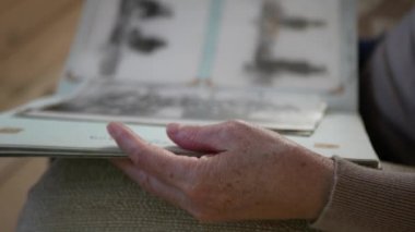 Yetişkin bir kadın evde eski bir fotoğraf albümü gibi görünüyor. Eski bir fotoğraf albümüyle yaşlı bir kadının eline yakından bakın. Yaşlılar fotoğraf albümünü inceliyor.
