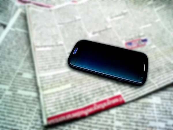 Zeitung und Smartphone verschwimmen lassen — Stockfoto