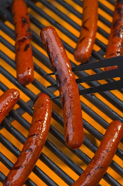 Deliciosos cachorros-quentes cozinhando em um churrasco quente flamejante — Fotografia de Stock