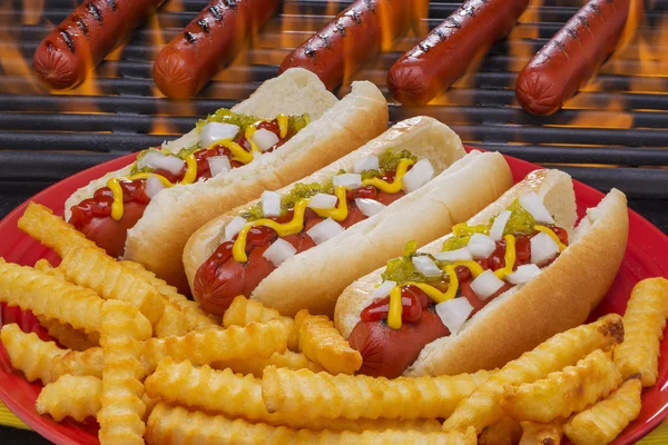 Três deliciosos cachorros-quentes com batatas fritas — Fotografia de Stock