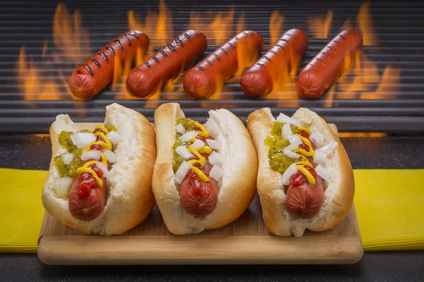 Tres deliciosos perritos calientes con parrilla Fondo de barbacoa —  Fotos de Stock