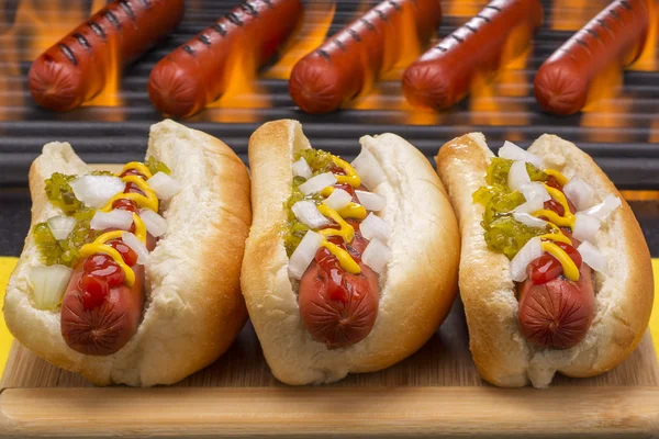 Tres deliciosos perritos calientes con parrilla Fondo de barbacoa —  Fotos de Stock