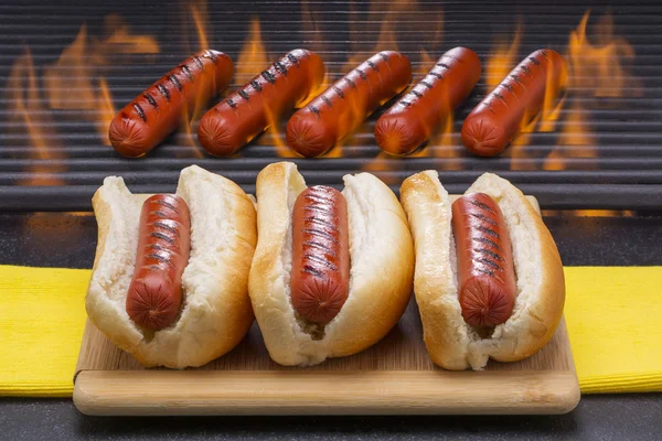 Tři hot dogy v přihrádkách s grilování, rožnění v pozadí — Stock fotografie