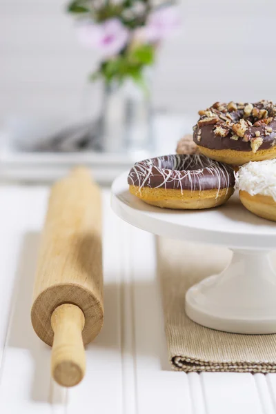 Donuts frescos em um pedestal branco em um cenário de cozinha em casa Imagem De Stock