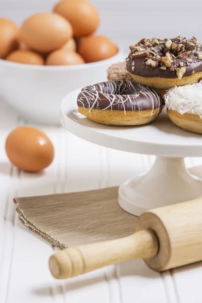Donuts frescos em um pedestal branco em um cenário de cozinha em casa Fotografias De Stock Royalty-Free