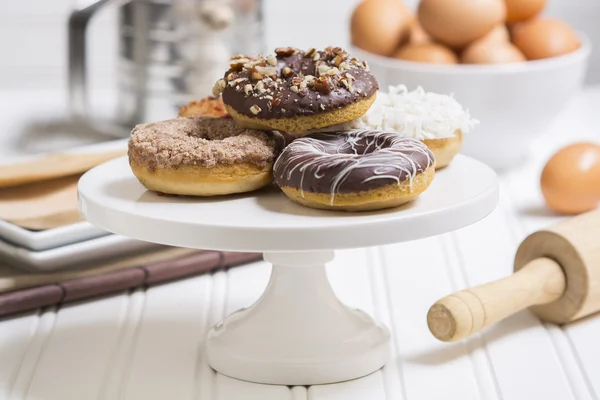 Donuts recién hechos en un pedestal blanco en un entorno de cocina casera Imagen De Stock