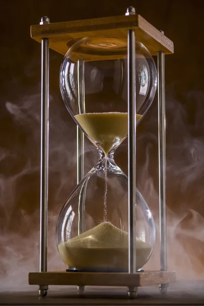 Reloj de arena con humo sobre un fondo rústico Imágenes de stock libres de derechos