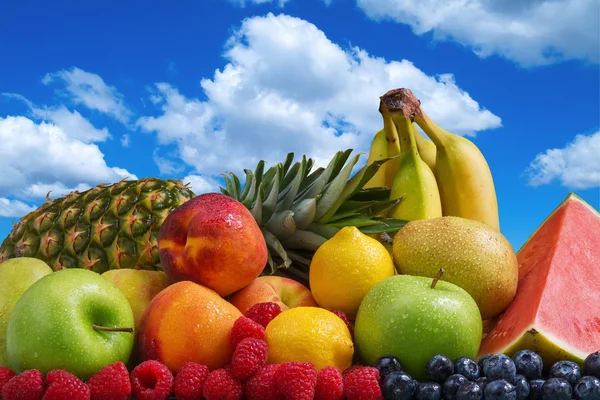 Assortiment de fruits exotiques et ciel bleu avec des nuages blancs gonflés Image En Vente