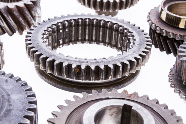 Large group of rusty transmission gears on a white background.