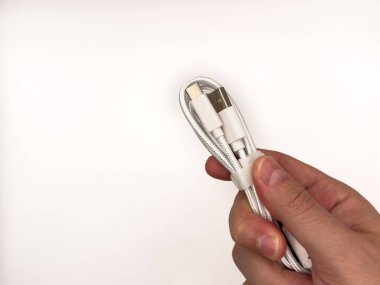 ABD tip C, USB tip A, mikro usb, şarj aletleri, tip C, beyaz usb, turuncu usb. İki farklı renk teli tutan bir el. Biri beyaz ve diğeri turuncu..