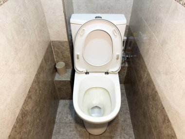 Banyoda beyaz seramik tuvalet, hiç kimse, ayrı tuvalet, tankın üstünde Avrupa sifonu, beyaz plastik tuvalet kenarı, umumi tuvalet. Yükseltilmiş kenar Yüksek kalite