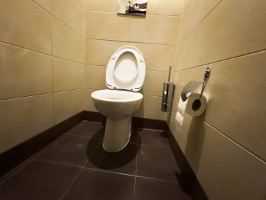 Banyoda beyaz seramik tuvalet, hiç kimse, ayrı tuvalet, duvarda Avrupa sifonu, beyaz plastik tuvalet kenarı, umumi tuvalet yükseltilmiş kenar. Yüksek kalite