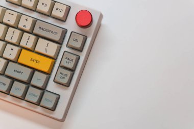 Beyaz arkaplanda parlak Enter tuşuna sahip beyaz mekanik klavye, minimalizm, klavye tuşları. Sarı tuşlu bir klavye. Yüksek kalite