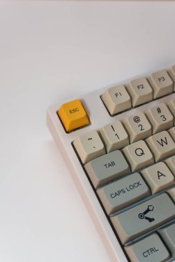 Beyaz arka planda parlak sarı Esc tuşlu beyaz mekanik klavye, minimalizm, klavye tuşları. Sarı tuşu ve kırmızı ses tuşu olan bir klavye. Yüksek kalite