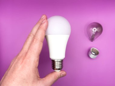 Modern LED lamba, elektrik tasarrufu. Tungsten ampul lambası. Çalışmayan ampul, kırık ampul. Aydınlık ve karanlık kavramı, fikir, elektrik kopyalama alanı, deri döşeme, üst görünüm mor zemin. Yüksek kalite