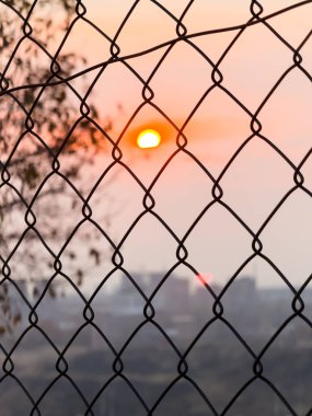 Şehirde günbatımı, metal bir çitin ardında güzel bir manzara, şehirde siyah metalden yapılmış bir çit. Yüksek kalite fotoğraf