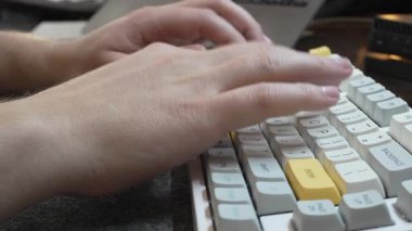 Ofis bir bilgisayarda çalışıyor, programcı beyaz bir klavyede hızlı yazıyor, yandan dokunuyor, evden uzaktan kumandayla çalışıyor, serbest olarak oturuyor. Yüksek 4k kalite