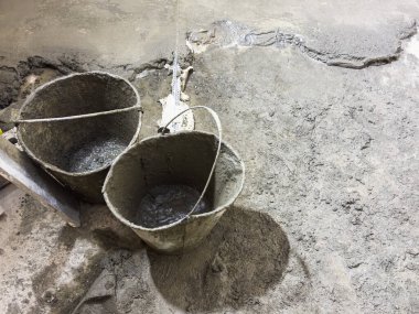 Çimento ve bir kova, yenileme yapılan bir dairede zemini döşemek için iki kova çimento, DIY onarım ve onarım. Yüksek kalite