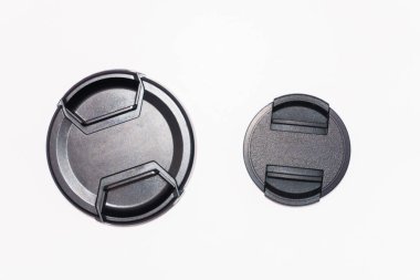 Two black camera lens caps of different sizes, a small and a large lens cap on a white background. High quality