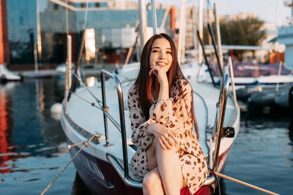 Güzel gülümseyen Asyalı genç bir kız, denizdeki bir iskelede bir teknede oturuyor. Portre