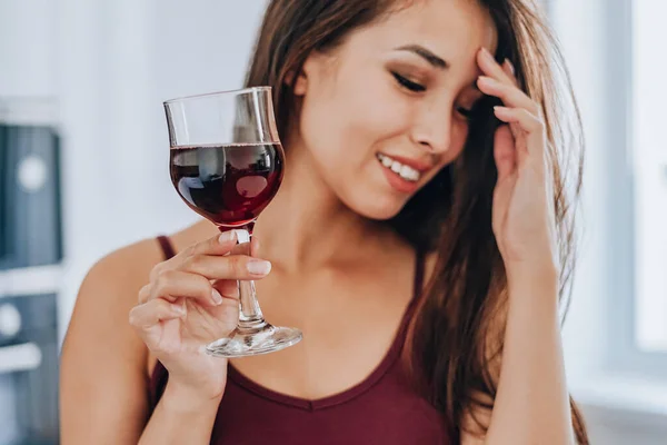 Asyalı kadın evde şarap içiyor. seçici odak