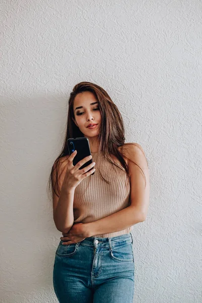 Mutlu bir Asyalı kadının portresi beyaz arka planda günlük kıyafetlerle cep telefonu kullanıyor.