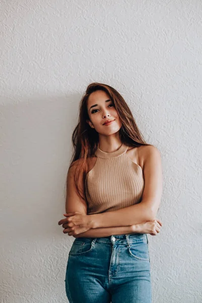 Beyaz bir arka planda günlük giysiler içinde mutlu bir Asyalı kadının portresi.