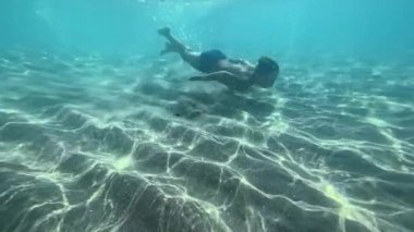 Çocuk elini suyun altında sallıyor.