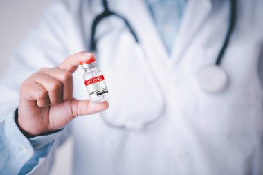 Tıp doktoru elinde aşı, sağlık hizmeti koyu mavi konsept, hastane çalışanı elinde kırmızı etiket aşısı şişesi şov dünyası konsepti..
