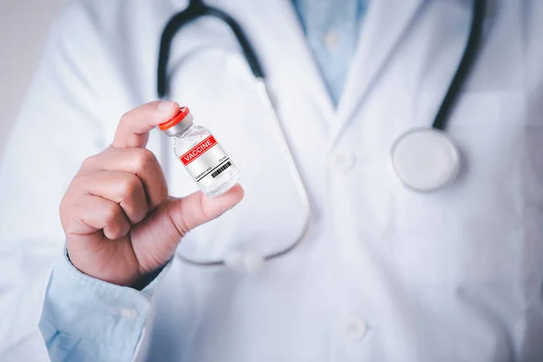 Medical doctor holding vaccine business healthcare dark blue concept, Hospital worker hand holding red label vaccine bottle show business concept.