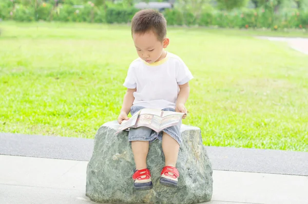 Junge liest gerne Buch im Freien Stockbild
