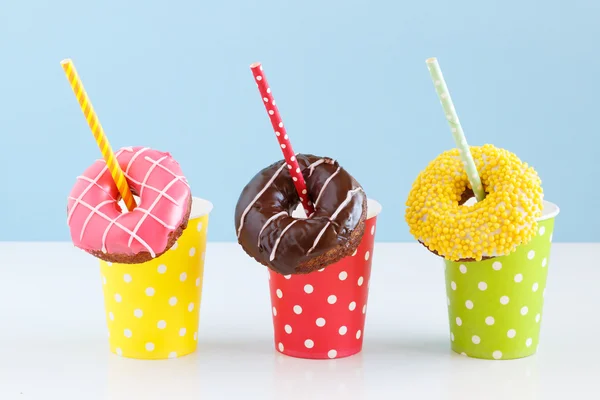 Donuts coloridos em um fundo azul. Copos coloridos com palhas de coquetel — Fotografia de Stock