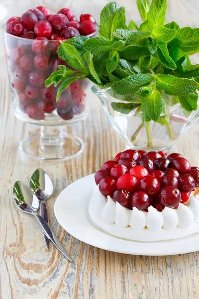 Glass of frozen cranberries. Portion of meringue cake with cream and cranberries — Stock Photo, Image