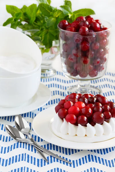 Meringue cake decorated with cranberries and mint. A glass of frozen cranberries — Stock Photo, Image
