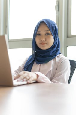 Ev kavramından yola çıkarak, Malezyalı kadın evde dizüstü bilgisayar kullanıyor.