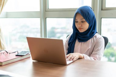 Ev kavramından yola çıkarak, Malezyalı kadın evde dizüstü bilgisayar kullanıyor.