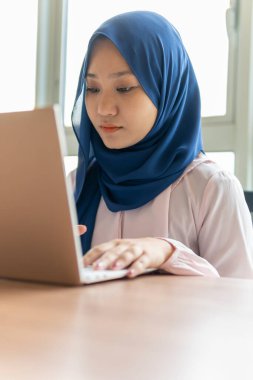 Ev kavramından yola çıkarak, Malezyalı kadın evde dizüstü bilgisayar kullanıyor.