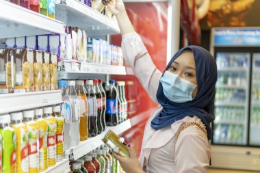 Yeni Normal kavram, alışveriş merkezindeki sevimli Malezyalı kız yüz maskesi takarak alışverişe gidiyor.