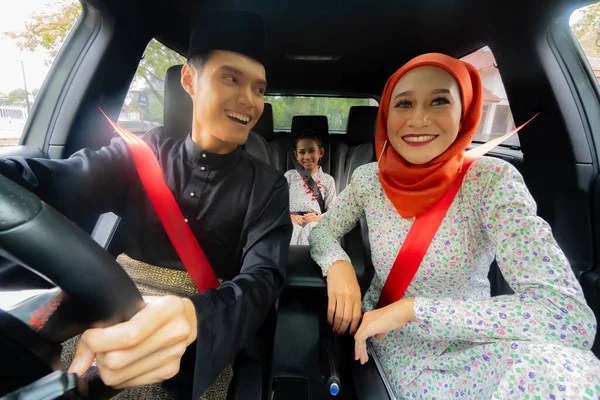 Malay family inside the car wearing traditional costume for Hari Raya festive