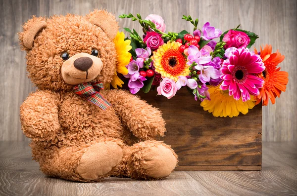 Flores en la caja y un osito de peluche — Foto de Stock