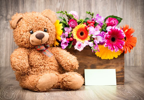 Bloemen in het vak en een teddybeer — Stockfoto