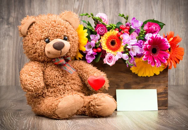 Fleurs dans la boîte et un ours en peluche — Photo