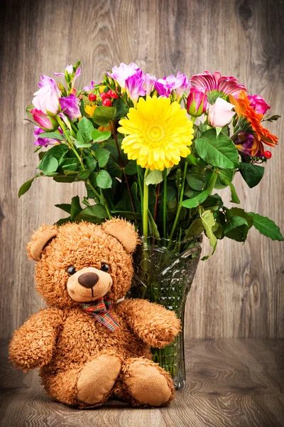 Urso de pelúcia e flores no vaso — Fotografia de Stock