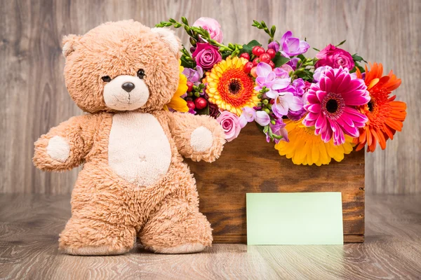 Flores en la caja y un osito de peluche — Foto de Stock