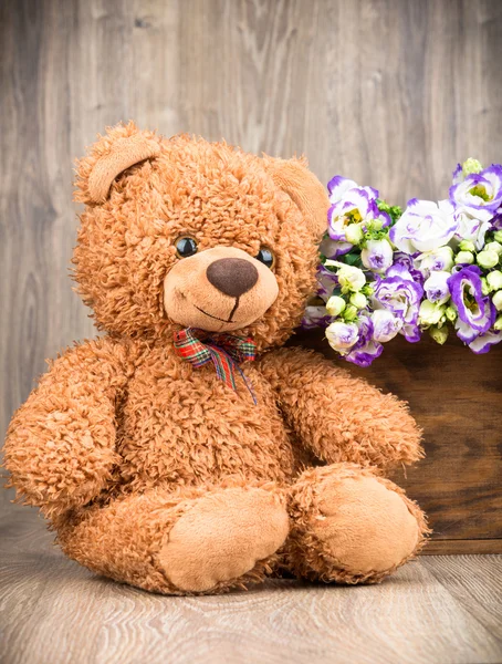 Flores na caixa e um urso de pelúcia — Fotografia de Stock