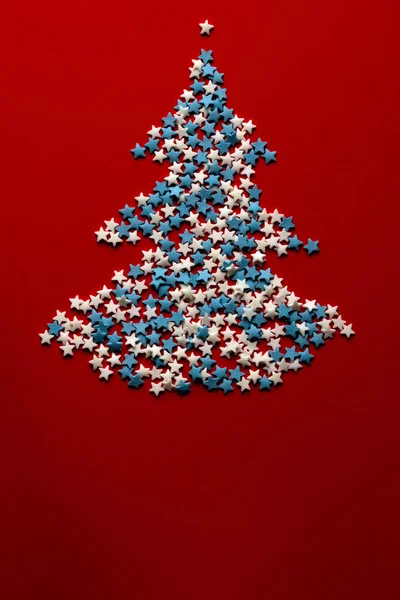 Kırmızı zemin üzerinde yıldızlardan yapılmış Noel ağacı