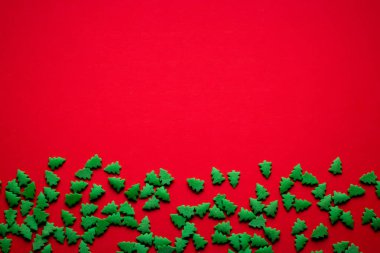 Kırmızı arka planda yeşil Noel ağaçları ve metin için yeri var.