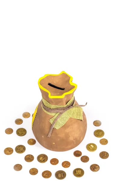 Keramische moneybox op een witte achtergrond met gouden munten rondom — Stockfoto