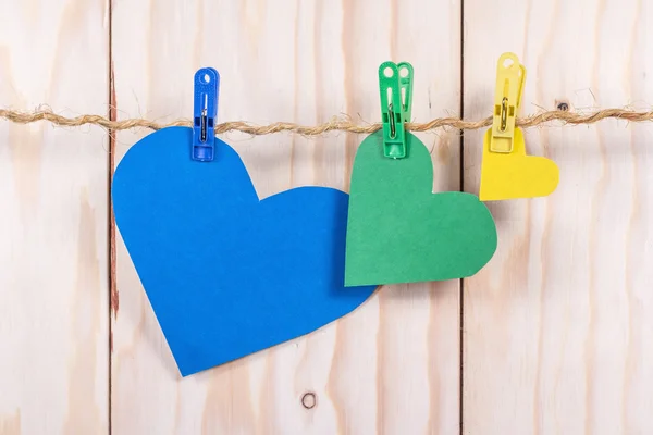 Цветные бумажные сердечки на веревке с прищепкой на деревянном фоне — стоковое фото