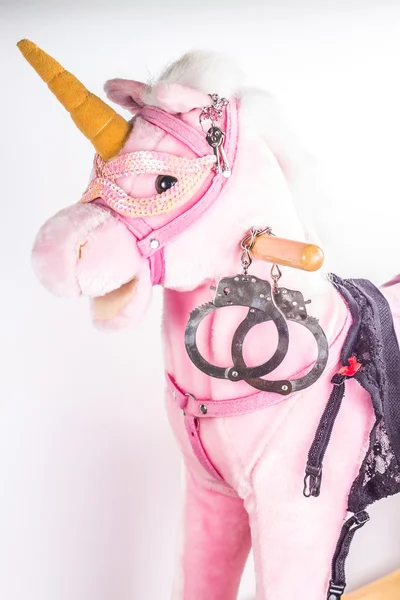 带着手铐在白色背景上的粉红独角兽玩具 免版税图库图片